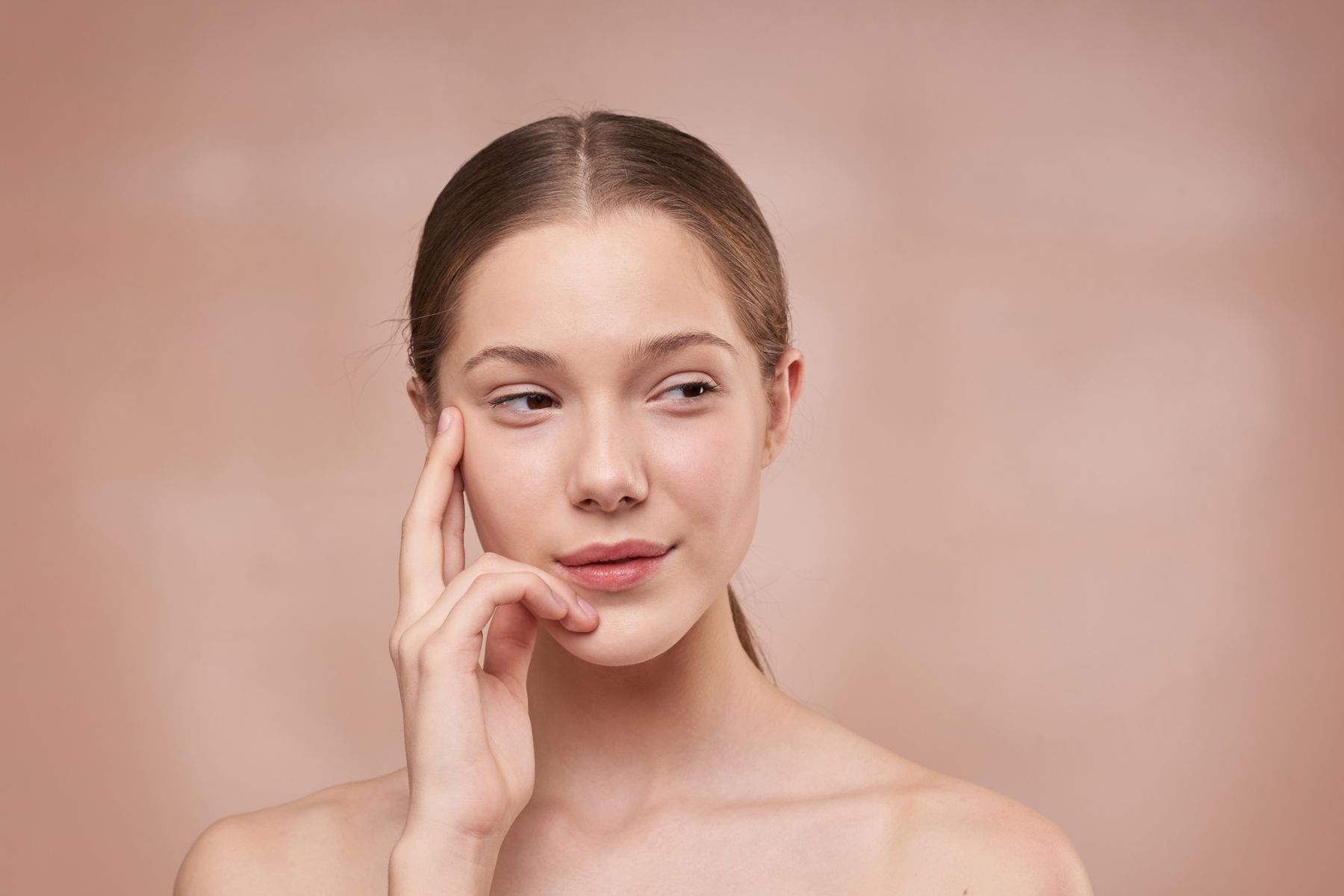 Studio portrait of a woman gently resting her fingers against her cheek